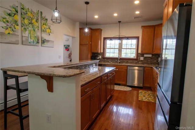 a kitchen with stainless steel appliances granite countertop a sink a stove and a wooden floor