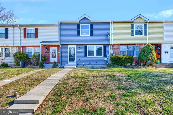 a view of a brick house with a yard plants and large tree