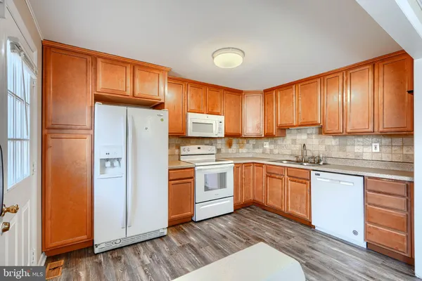 a kitchen with stainless steel appliances granite countertop a refrigerator a sink dishwasher and wooden cabinets with wooden floor