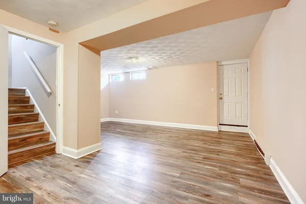a view of an empty room with wooden floor and stairs