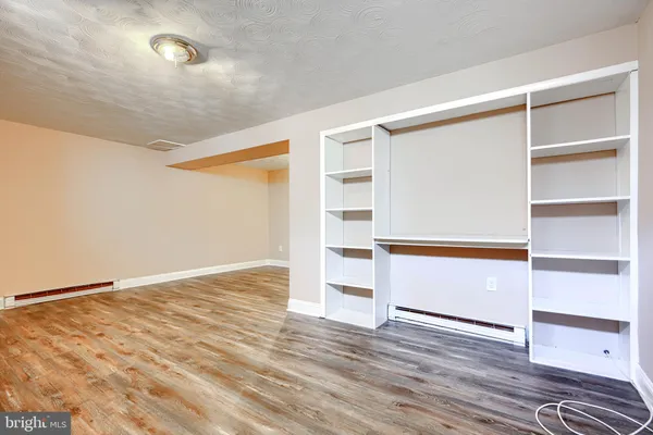 a view of an empty room with wooden floor and closet