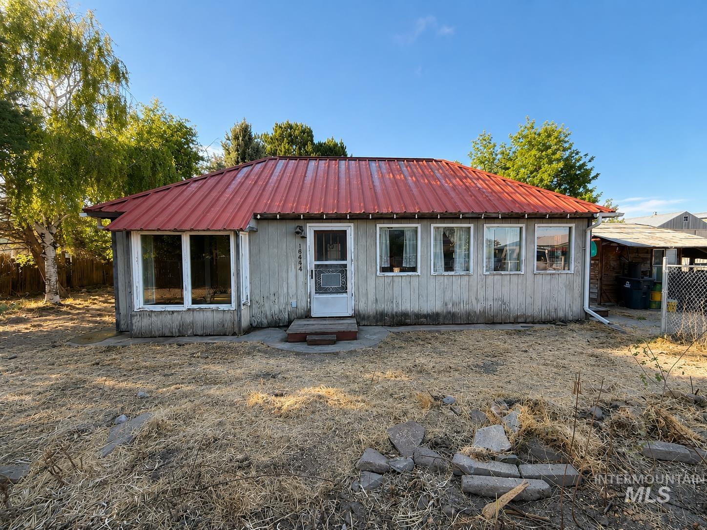 16434 Pride Lane Caldwell, ID 83607 - Photo 1 of 16 Single-story home featuring a red corrugated metal roof and white siding
