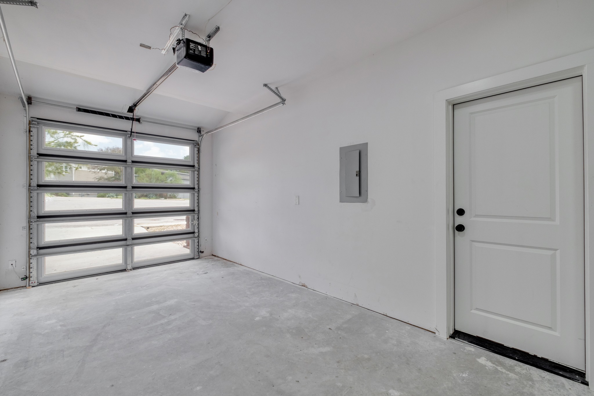 5211 Rob-Scott Street Austin, TX 78721 - Photo 13 of 24 A well-lit garage features a modern glass panel door and clean concrete flooring.