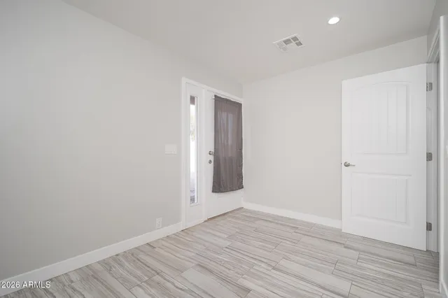 a view of an empty room with wooden floor and closet