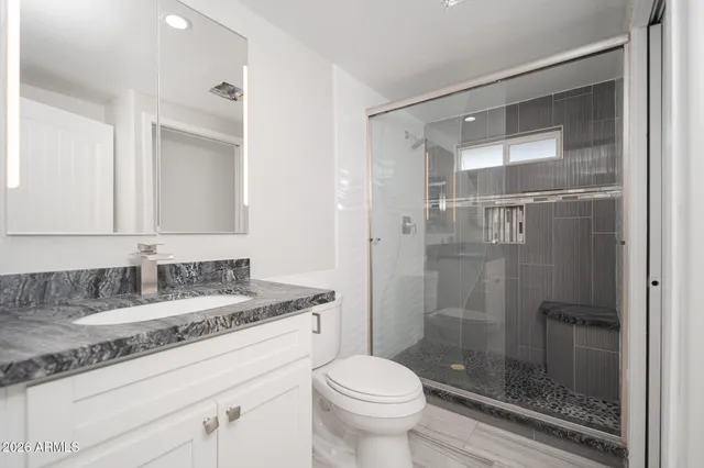 a bathroom with a granite countertop sink toilet and shower