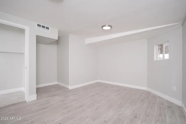 an empty room with wooden floor and windows