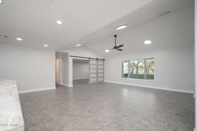 an empty room with windows and ceiling fan