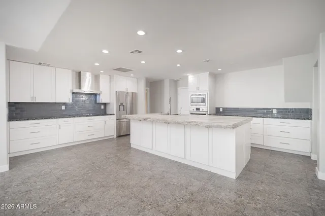 a large kitchen with stainless steel appliances granite countertop a white stove top oven and white cabinets