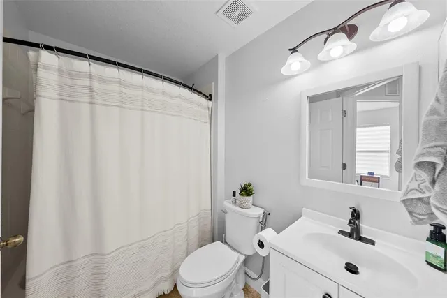 a bathroom with a sink a toilet and shower curtain