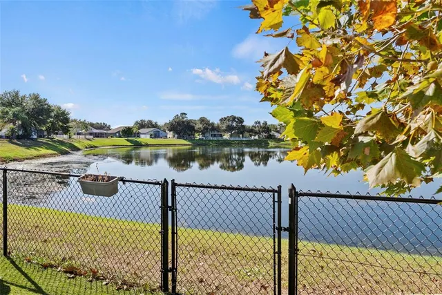 a view of a lake with lawn chairs and wooden fence