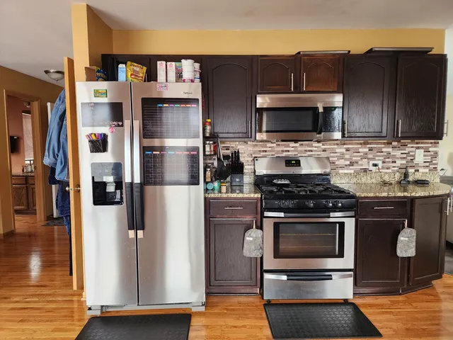 a kitchen with stainless steel appliances granite countertop a refrigerator stove and cabinets