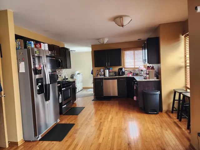 a kitchen with stainless steel appliances a stove a refrigerator a sink a oven with wooden floor