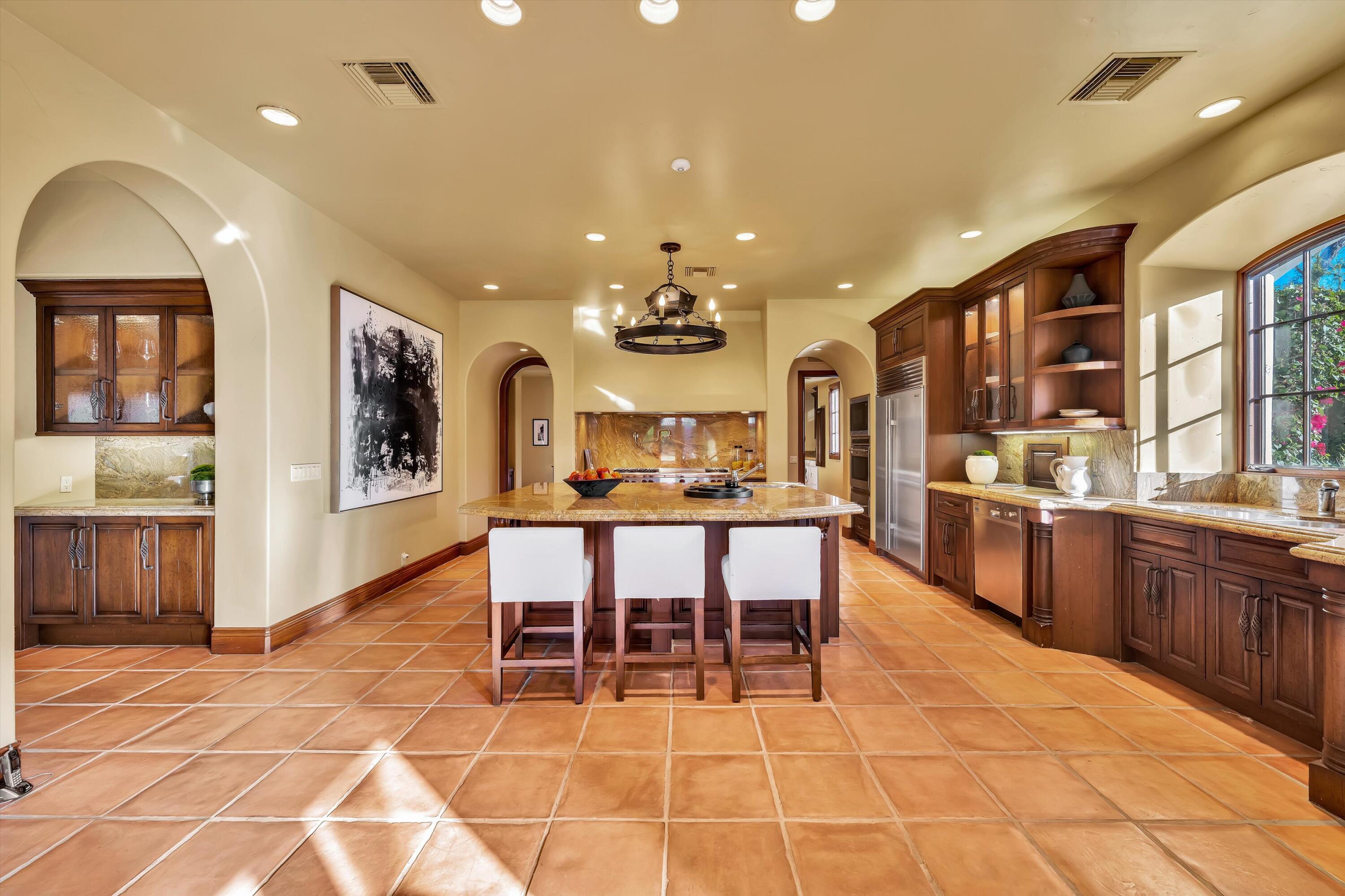 2 Serrano Way Rancho Mirage, CA 92270 - Photo 45 of 76 a kitchen with stainless steel appliances kitchen island granite countertop a sink and cabinets