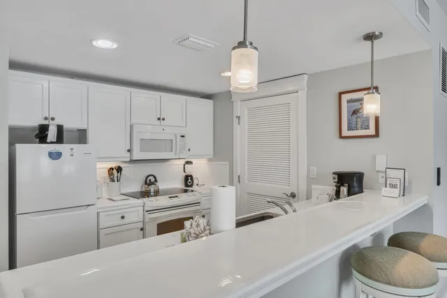 a kitchen with kitchen island a white cabinets and white appliances