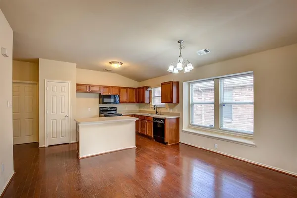 a kitchen with stainless steel appliances granite countertop a stove top oven a sink dishwasher and a refrigerator with wooden floor