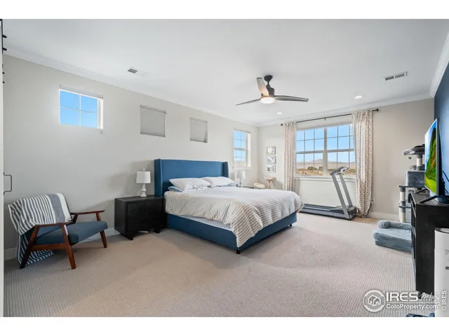 a spacious bedroom with a bed a couch and potted plant on the dresser