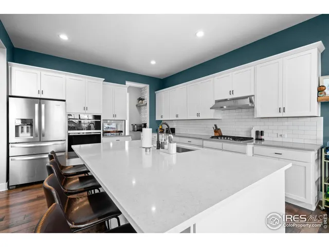 a kitchen with stainless steel appliances granite countertop a refrigerator and a stove top oven