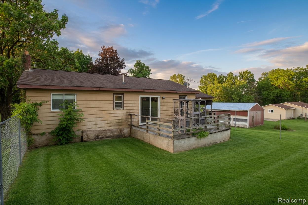 8040 Smith Road Gaines, MI 48436 - Photo 16 of 30 Expansive green lawn with mature trees and a chain-link fence