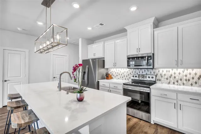 a kitchen with stainless steel appliances a table chairs and white cabinets