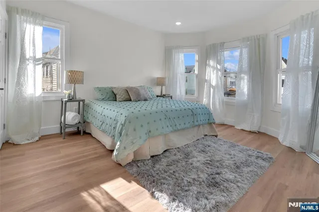 a spacious bedroom with a bed and a dresser with wooden floor