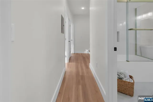 a view of a hallway with wooden floor and a bathroom