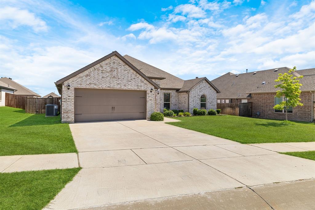 915 Timber Ridge Drive Justin, TX 76247 - Photo 2 of 39 Brick exterior with an arched window accent, a two-car garage, and a concrete driveway