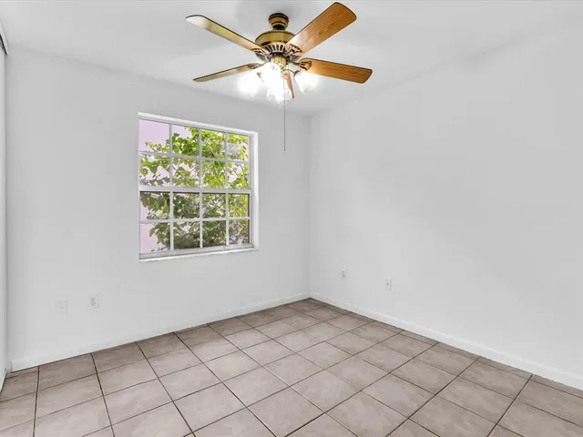 an empty room with windows and fan