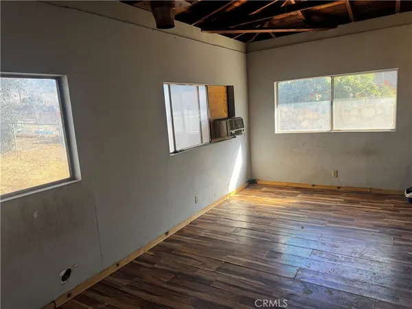 a view of empty room with window and wooden floor