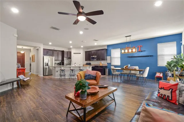 a living room with furniture kitchen view and a wooden floor