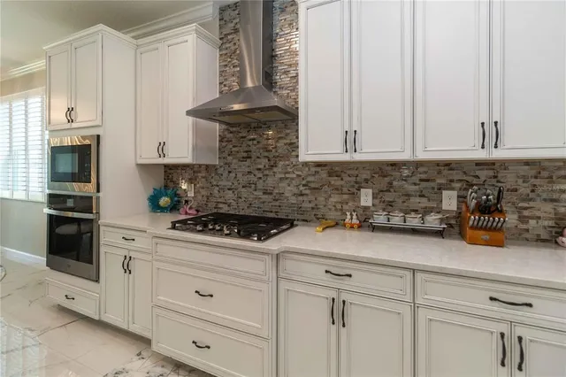 a large white kitchen with a large island oven a stove and a sink