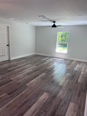 an empty room with wooden floor cabinet and windows