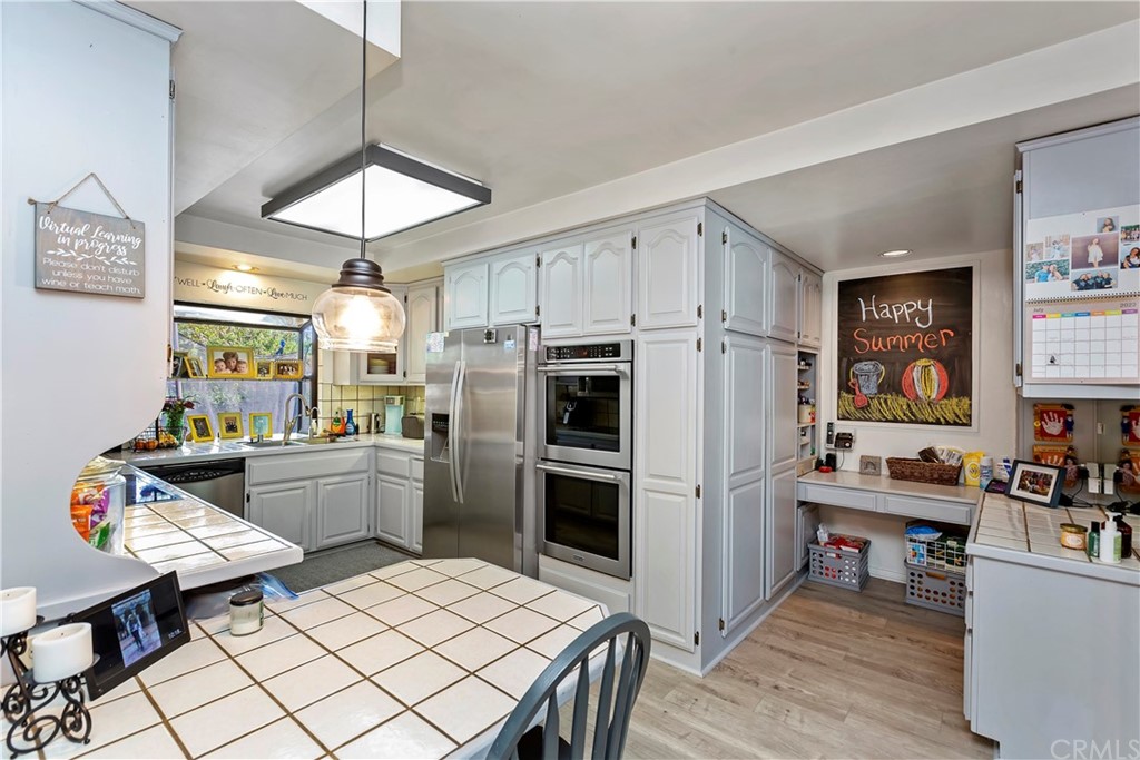 5201 Coventry Drive Riverside, CA 92506 - Photo 22 of 42 a kitchen with a refrigerator a stove a dining table and chairs with wooden floor