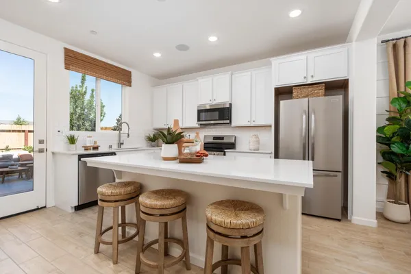a kitchen with sink refrigerator dining table and chairs