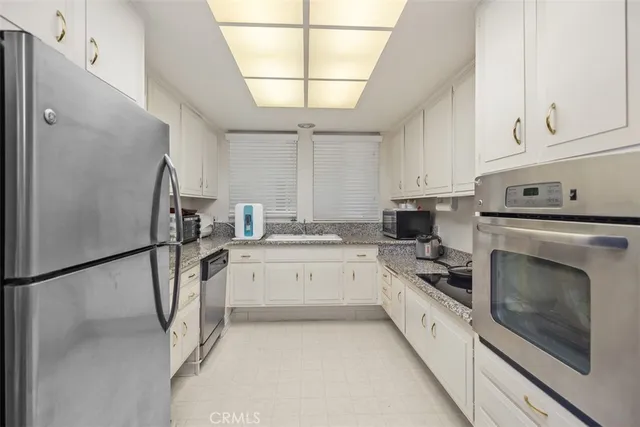 a kitchen with granite countertop white cabinets and white appliances