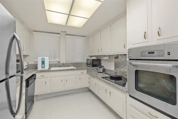 a kitchen with granite countertop white cabinets and a sink