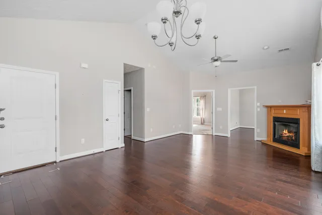 a view of an empty room with wooden floor and fireplace