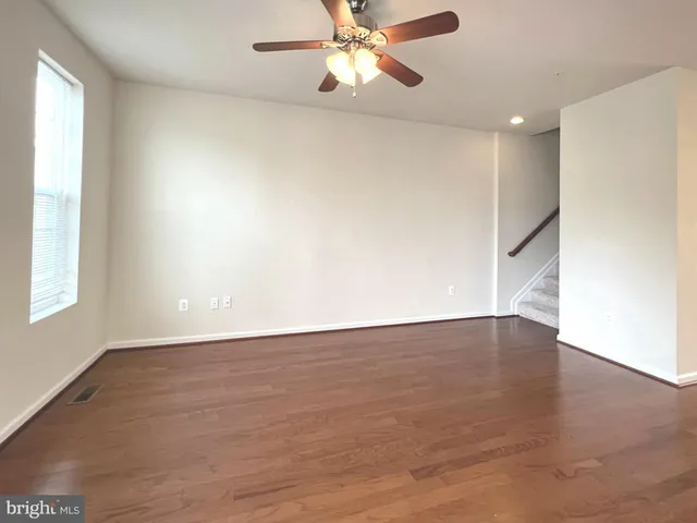 an empty room with wooden floor fan and windows