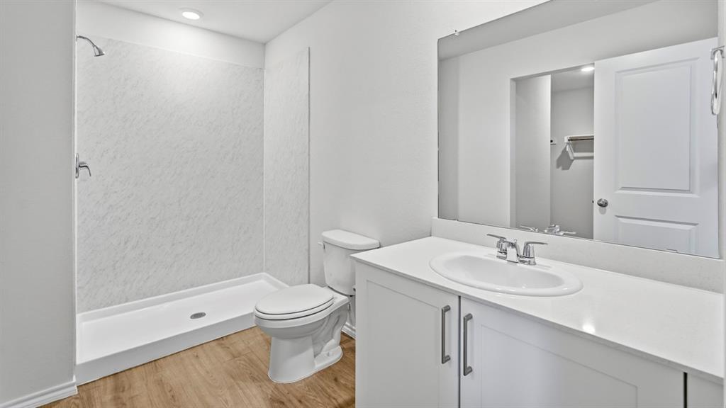 3535 Spring Time Street Forney, TX 75126 - Photo 15 of 23 Bathroom featuring a walk-in shower with a white textured surround, a white vanity with integrated sink, chrome fixtures, and wood-finish flooring