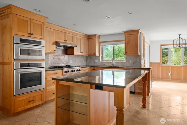 a kitchen with kitchen island granite countertop a stove a sink and a refrigerator