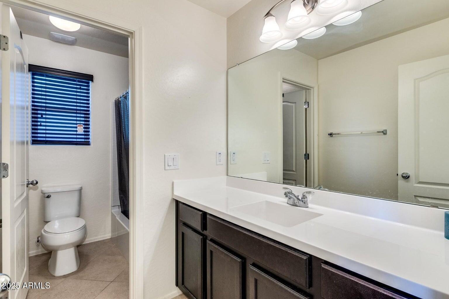 12057 West Rowel Road Peoria, AZ 85383 - Photo 13 of 20 a bathroom with a sink a toilet and a mirror