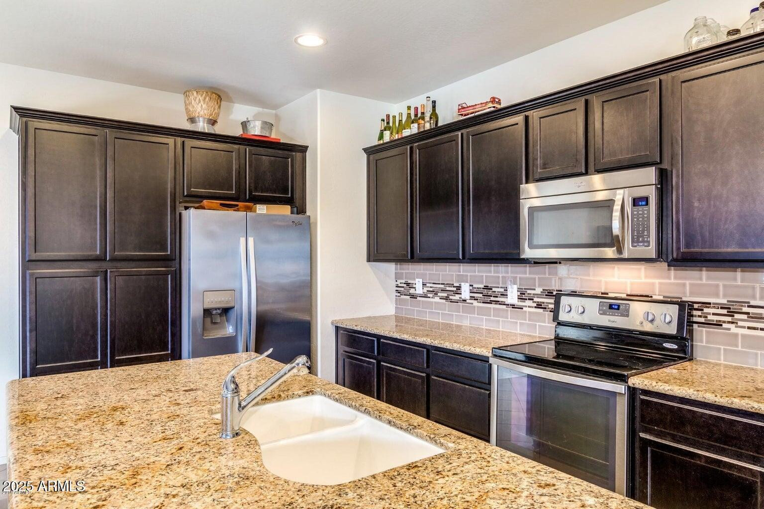 12057 West Rowel Road Peoria, AZ 85383 - Photo 7 of 20 a kitchen with stainless steel appliances kitchen island granite countertop a stove refrigerator and microwave
