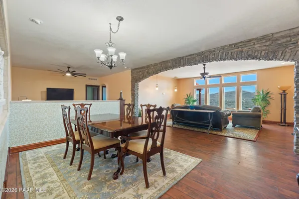 a dining room with wooden floor a chandelier a glass table and chairs