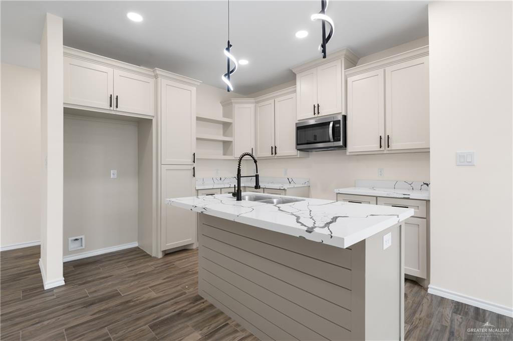 18054 Spruce Street Combes, TX 78552 - Photo 7 of 25 Modern kitchen featuring a central island with a waterfall-edge countertop, an integrated sink, and an articulating faucet