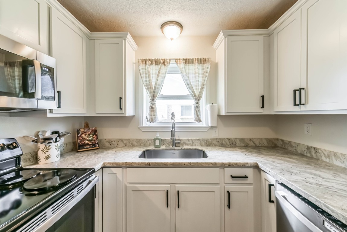323 Coventry Lane Alvin, TX 77511 - Photo 12 of 37 a kitchen with stainless steel appliances granite countertop a sink a stove and cabinets