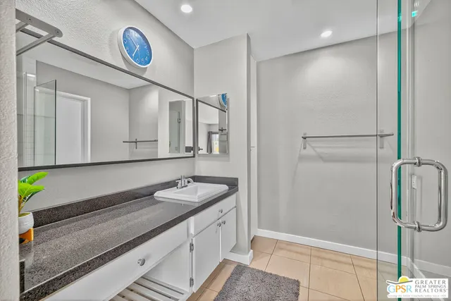 a bathroom with a granite countertop sink a mirror and a shower