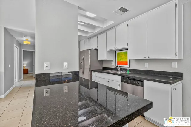 a large kitchen with granite countertop a stove a sink and a refrigerator