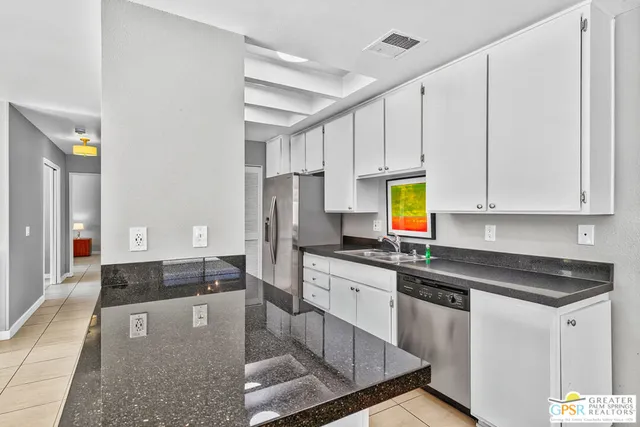 a kitchen with stainless steel appliances granite countertop a stove white cabinets a sink and dishwasher