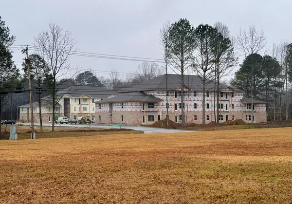 a front view of a building with lake view and trees