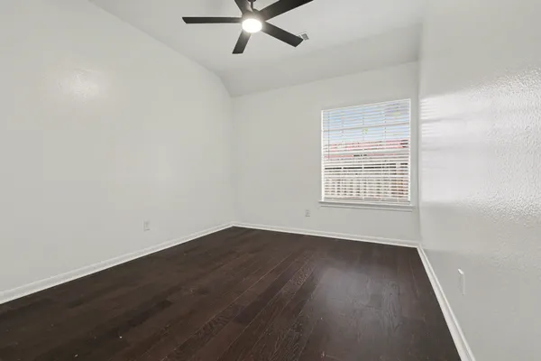 an empty room with wooden floor fan and windows