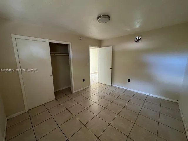 a view of an empty room with window and cabinet